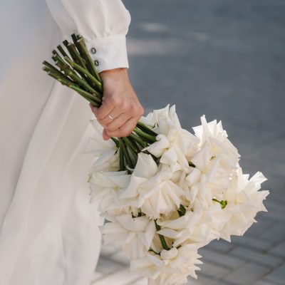 Wedding bouquet in the bride’s hands with white flowers roses on the background street. Handed a nice bouquet. Wedding bouquet in the bride's hands with white flowers roses on the background street. Handed a nice bouquet.